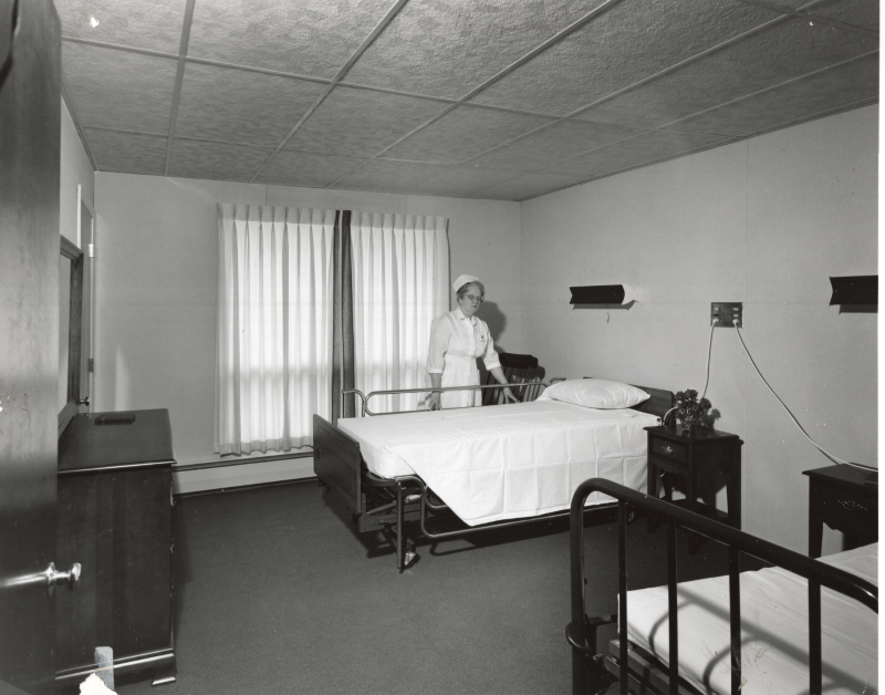 A nurse prepares a patient's bed at Highway Home for the Aged