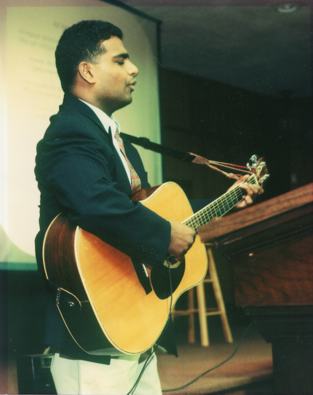 Pastor Finney Kuruvilla plays a guitar and leads a worship song