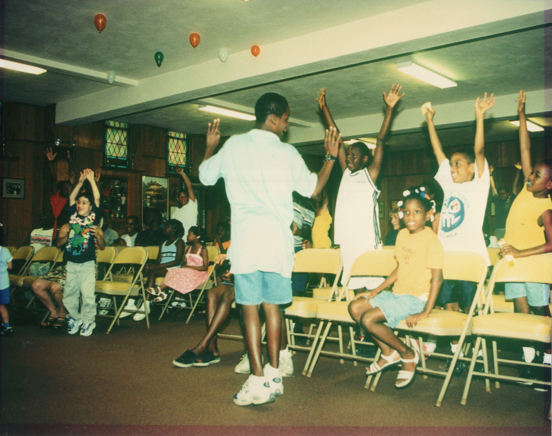 Children are led in song and dance with balloons