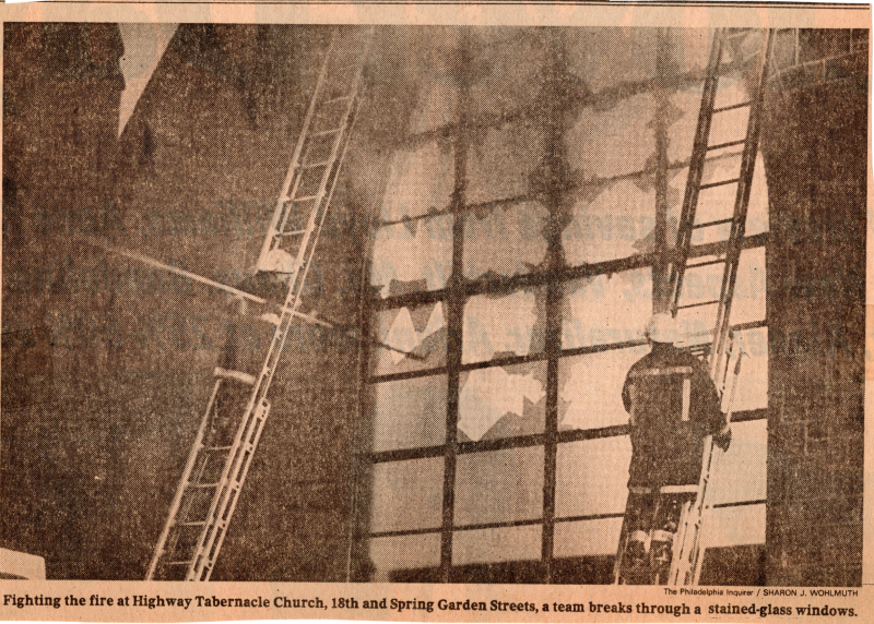Image of firefighters on ladders fighting the fire through broken glass windows