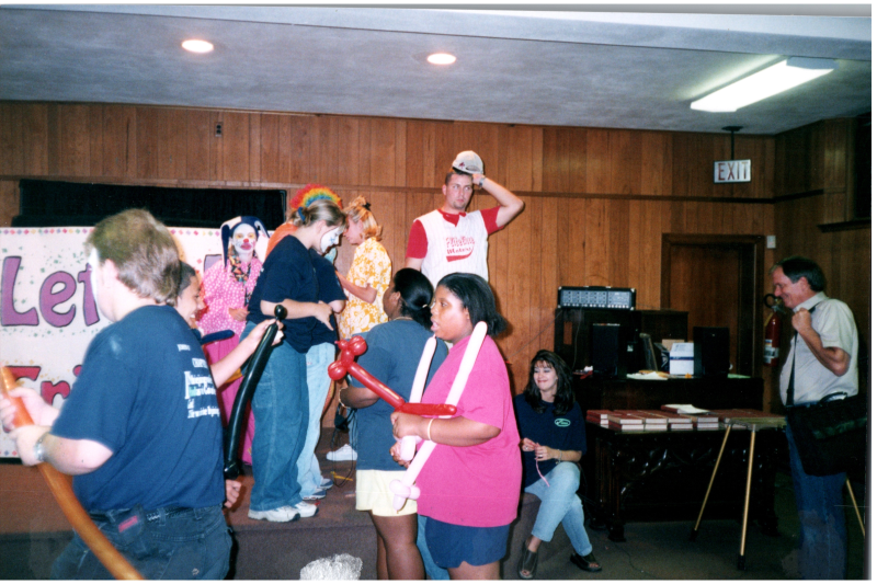 Balloon animals and clowns with a sign reading "Let's Be Friends"