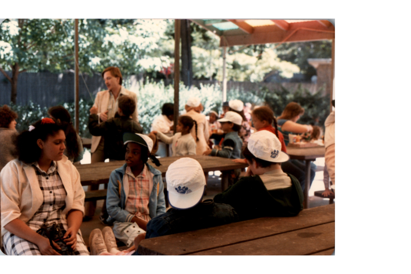 A group of children speak together at picnic tables at the zoo