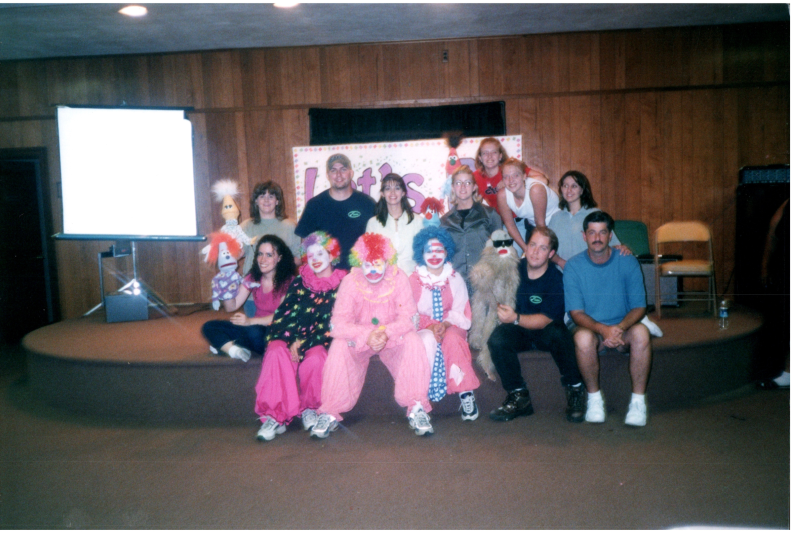 Group portrait of adult leaders with puppets and clown costumes. Back: Dana, Jason, Fawnda, April, Megan, Ashley, Rene. Front: Kimby, Sara, Johnny, Asleyn, Jonathan, and Lloyd
