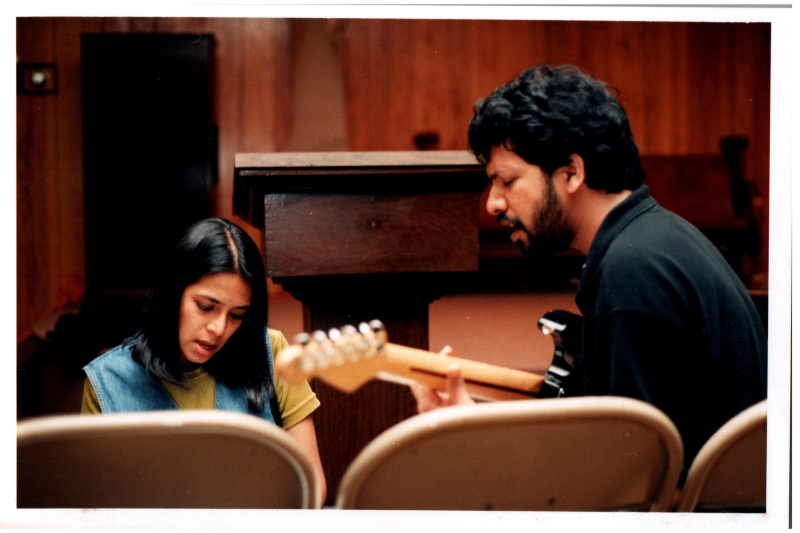 A man plays the guitar and sings with a woman