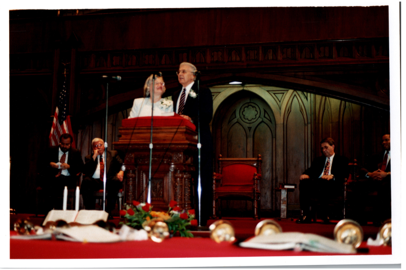 Pastor and Mrs. Bogdan speak with Pastor Wegner, Otis A. Fortenberry, and two other men seated behind them