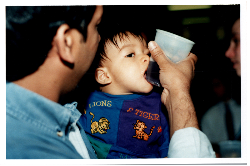 Baby held by a man licking a cup