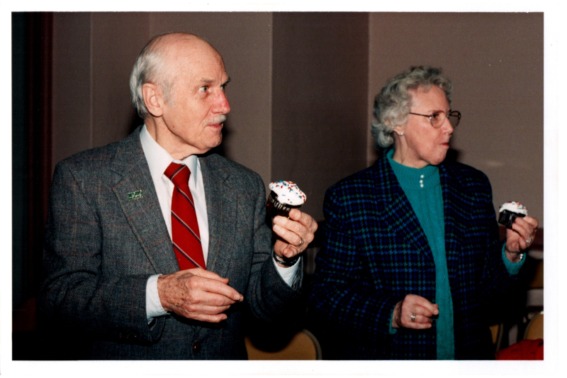 An older man and woman eat cupcakes
