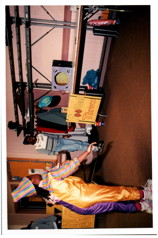A woman in a clown costume throws a football