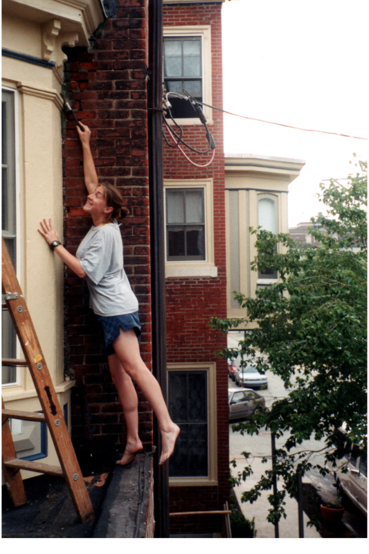 A woman paints the parsonnage exterior
