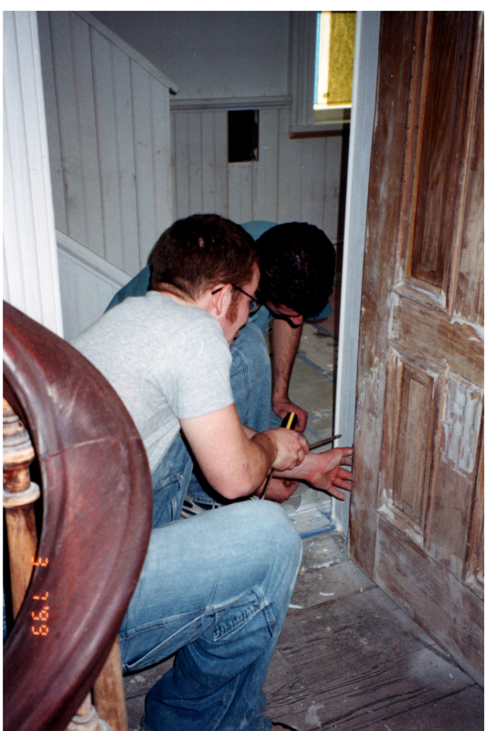 Two men work on door hinges