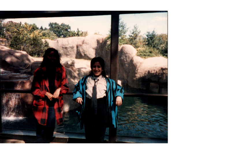 Two women smile in front of an enclosure
