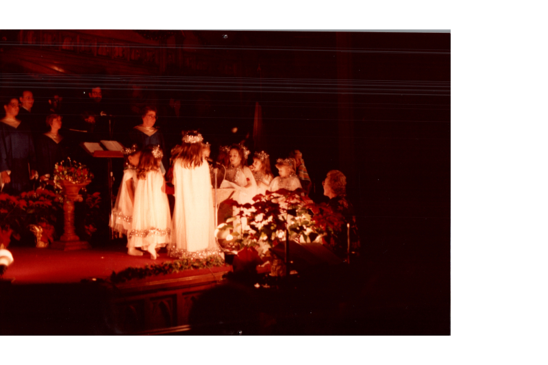Members of the choir sing while children dressed as angels stand around a cradle
