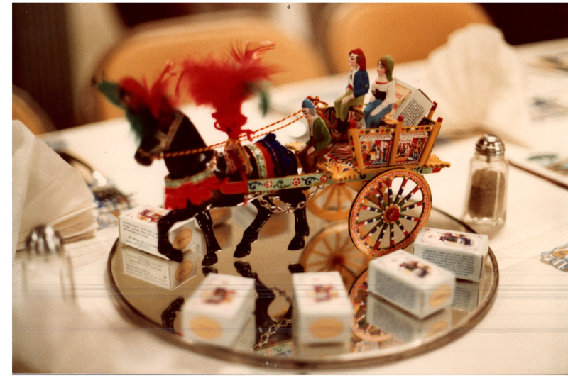 A horse pulls figurines on a metal plate surrounded by small boxes