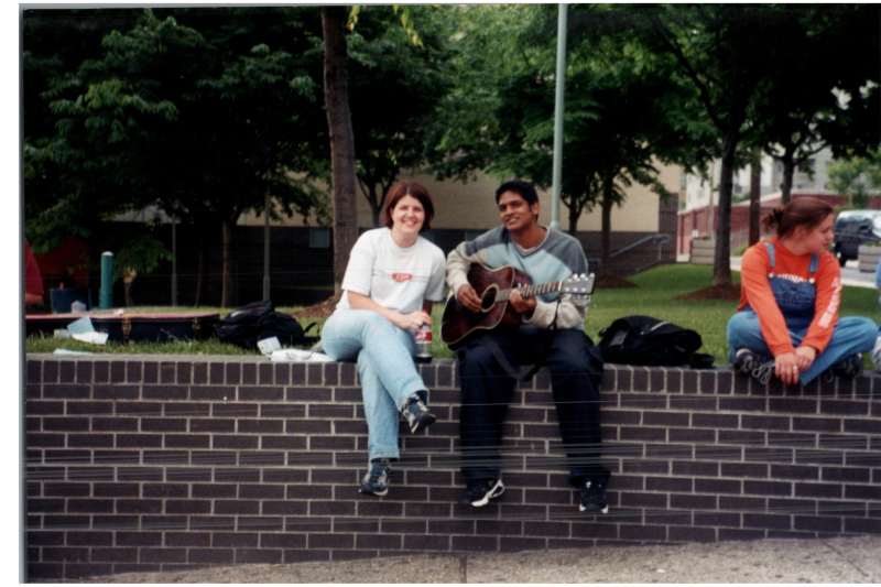A woman smiles with a man playing a guitar