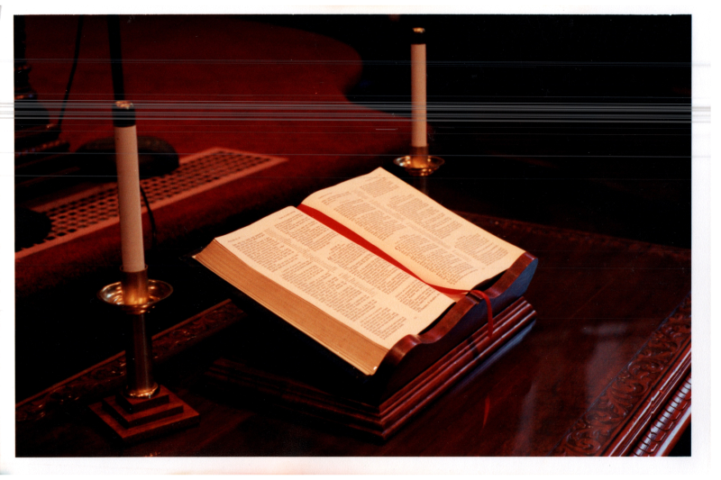 Photograph of a Bible in the sanctuary next to two candleholders