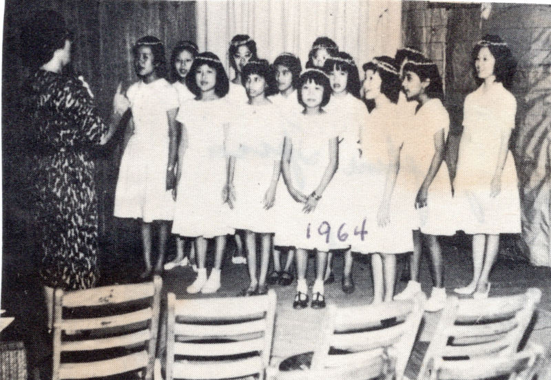 Image of a group of girls singing with the caption, "Josephine Spina, Christmas 1964"