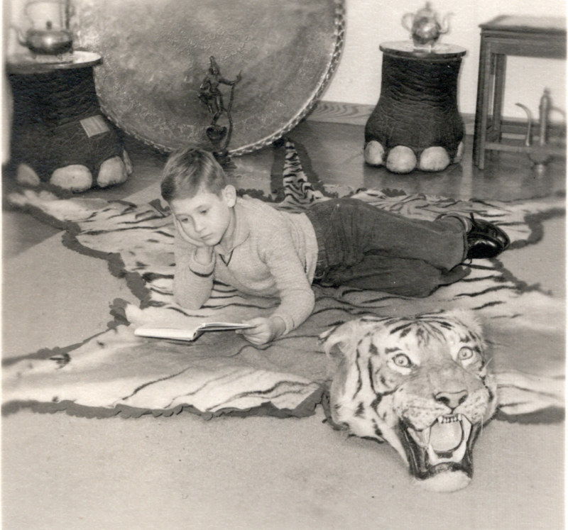 Image of Richard McDearmid, son of missionaries to India, Andrew and Bernice McDearmid, reading a book on a tiger-skin run