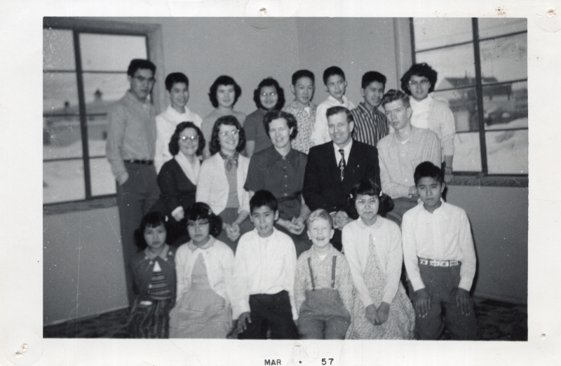 Photograph of Ruth Tomko, missionary to Alaska, with a group. Caption reads, "A recent picture of the children and workers. The managers, Mr. and Mrs. Haughton are seated in the center."