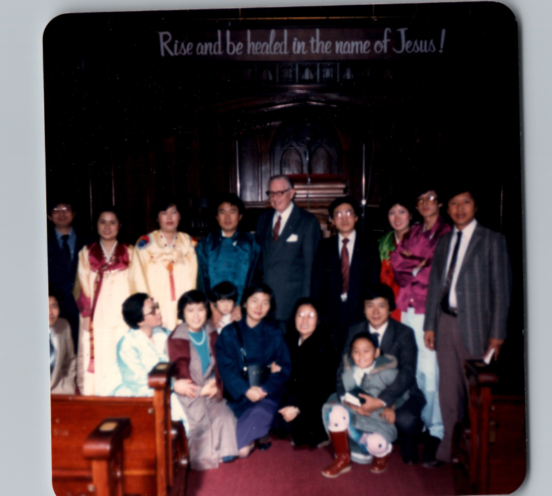 A group with several people dressed in traditional Korean clothing smile together in the sanctuary