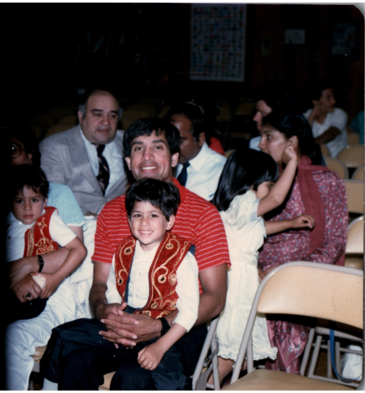 A man smiles with a young boy in his lap