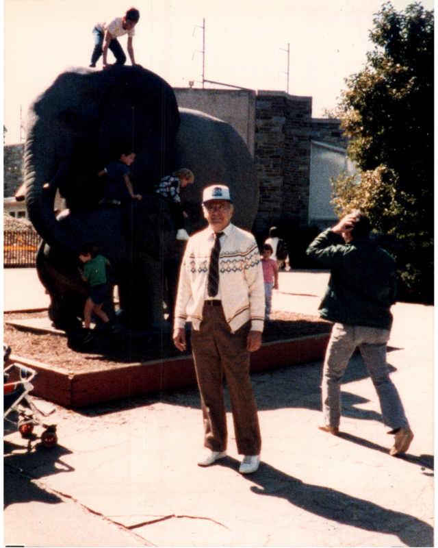Rev. Bogdan smiles while children climb an elephant sculpture in the background