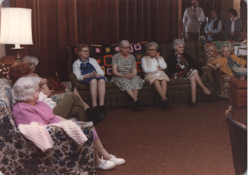 A group of older women sit together on couches