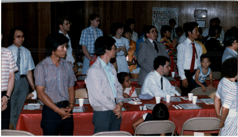 Congregants stand together around dinner tables