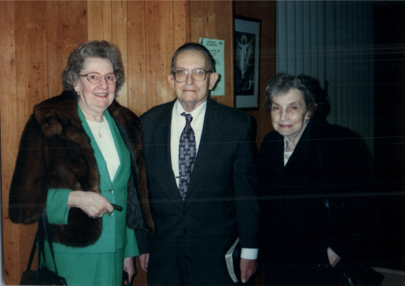Two older women and a man stand together