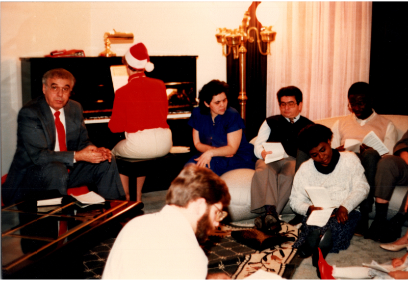 A woman in a santa hat plays the piano while congregants follow along with sheets of paper