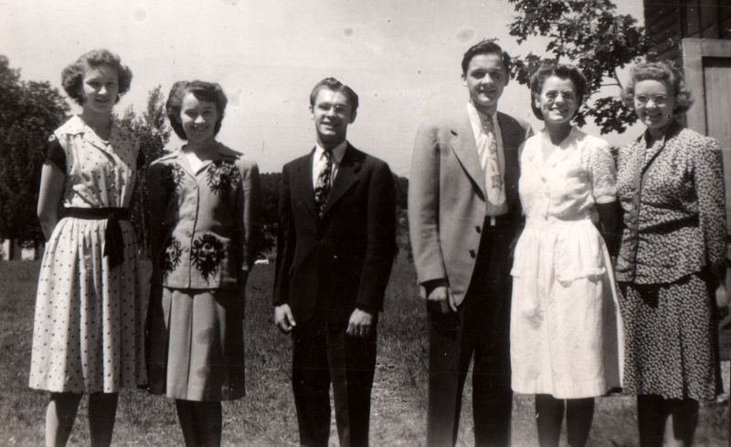 A group of four girls and two boys smile together