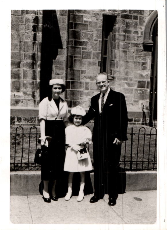 A man, woman, and child smile together outside of the church building