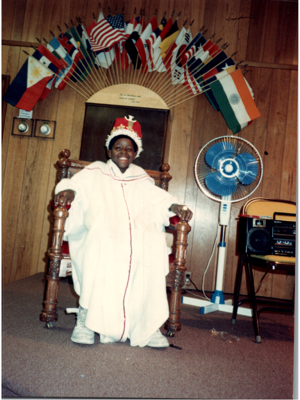 A boy in a crown sits on a throne