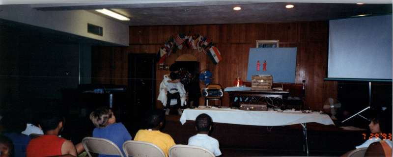 Children face Mrs. Abe Oliver on a stage