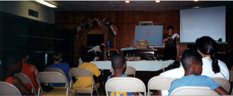 Children face Mrs. Abe Oliver on a stage