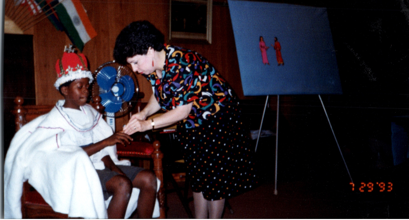 Mrs. Abe Oliver interacts with a boy in a crown sitting on a throne
