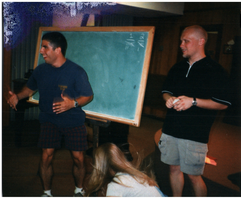 Mike Wulin and a man stand in front of a chalkboard