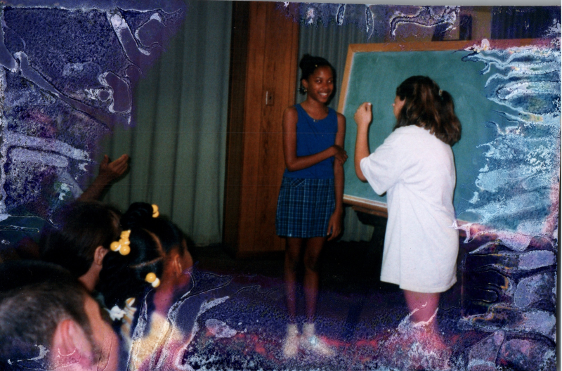 Two girls stand at a chalkboard