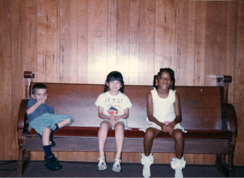 Three children sit on a pew
