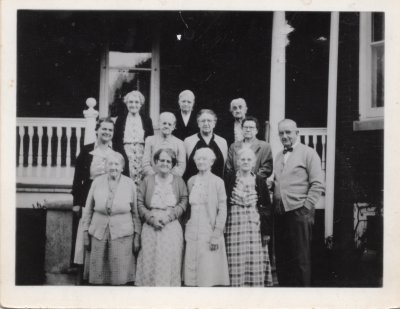 A group of older men and women smile for a group photo outside of Highway Home for the Aged