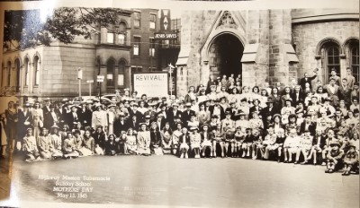 First of four image slices with congregants outside of the building at 19th and Green Streets with a revival banner in the background and Highway's "Jesus Saves" sign hanging